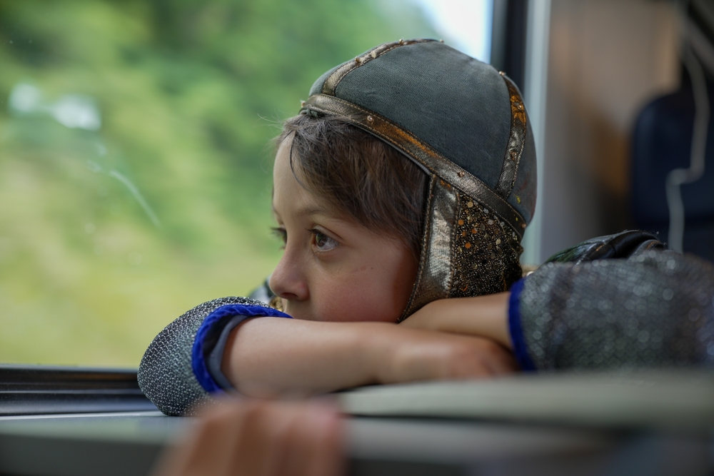 A young child rides a bus with an armored helmet on.