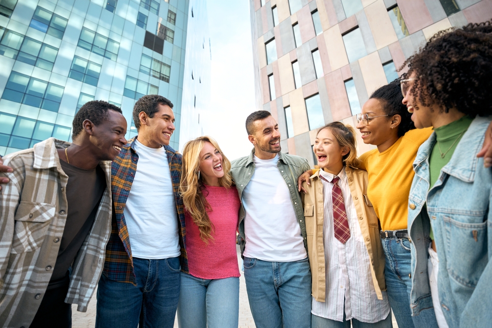 A diverse group of people embrace outside.